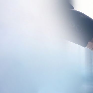 blaugraue Fläche und im Hintergrund zwei sich schüttelnde Männerhände